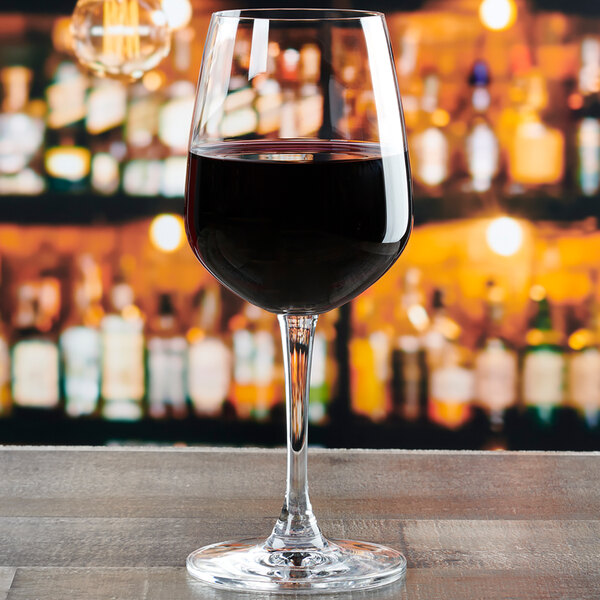 An Anchor Hocking Florentine II all-purpose wine glass filled with red wine on a table in a bar.