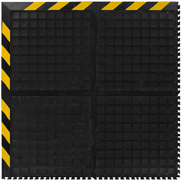 A black and yellow square M+A Matting anti-fatigue mat with black striped border.