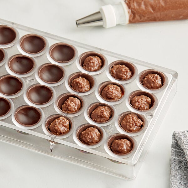 A close up of brown Cacao Barry Cara Crakine filling in a plastic container.