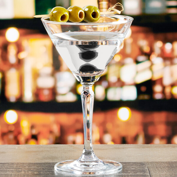 An Anchor Hocking Cienna martini glass with green olives on a table.