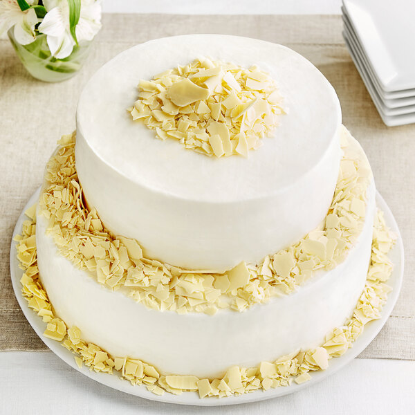 A white cake with Mona Lisa ivory chocolate shavings on top.