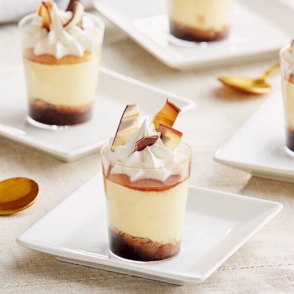 Three small dessert cups topped with Mona Lisa marbled chocolate shavings on a white plate.