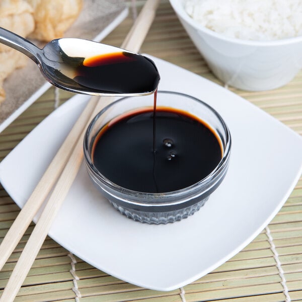 A spoon pouring La Choy Soy Sauce into a bowl of food.