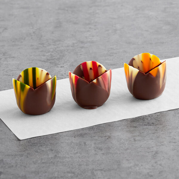 Three marbled chocolate tulip cups with colorful designs on them.