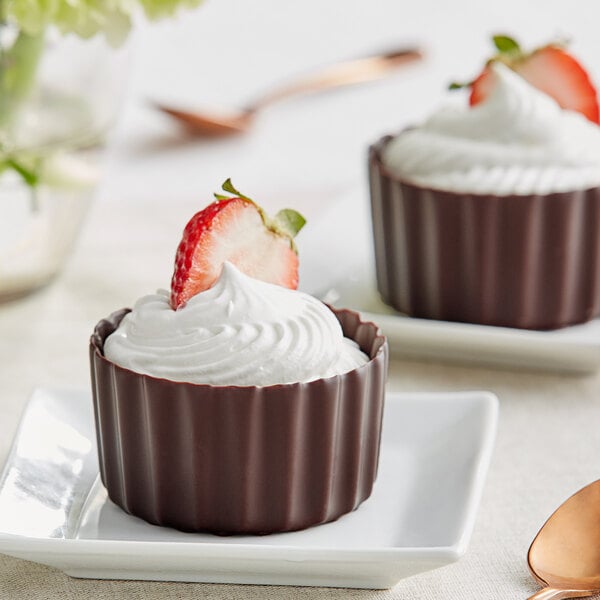 Two Mona Lisa dark chocolate cups with strawberries on top.