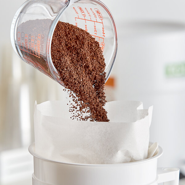 A measuring cup of Toddy Colombian Cold Brew Coarse Ground Coffee being poured into a paper bag.