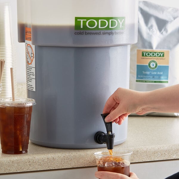 A person pouring Toddy Blend Low Acid Cold Brew Coffee into a glass.