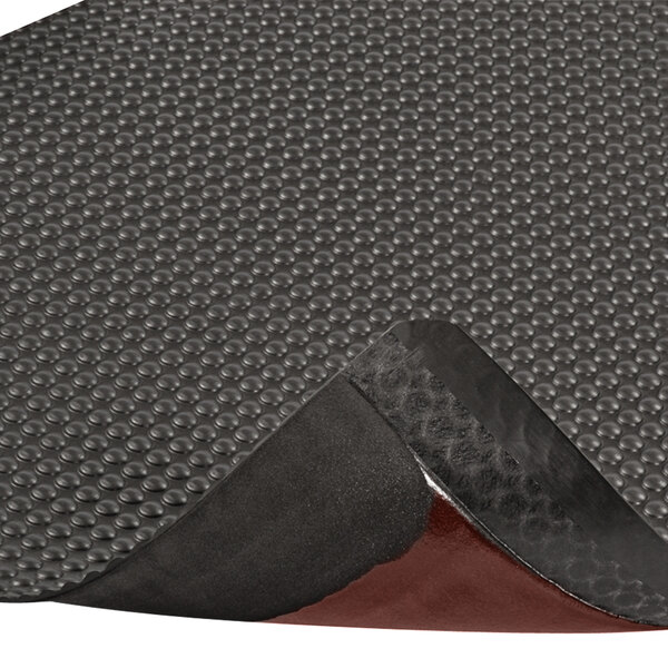 A close-up of a black Notrax Bubble Trax anti-fatigue mat with a red border.