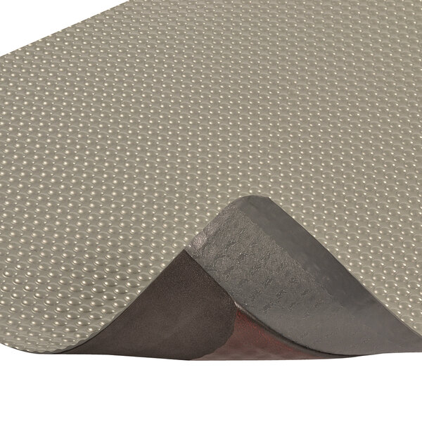 A close-up of a gray and black Notrax Bubble Trax anti-fatigue mat with a hole in it.