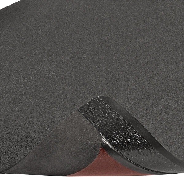 A close-up of a black Notrax anti-fatigue mat with a red edge.