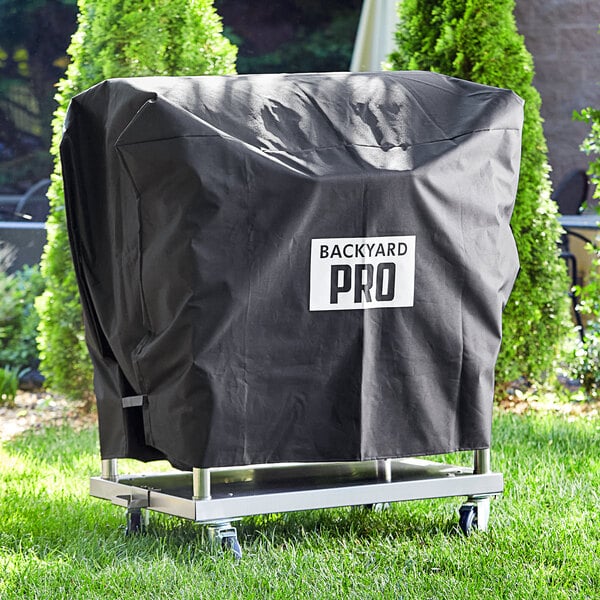 A black Backyard Pro vinyl cover on a grill cart in a yard.