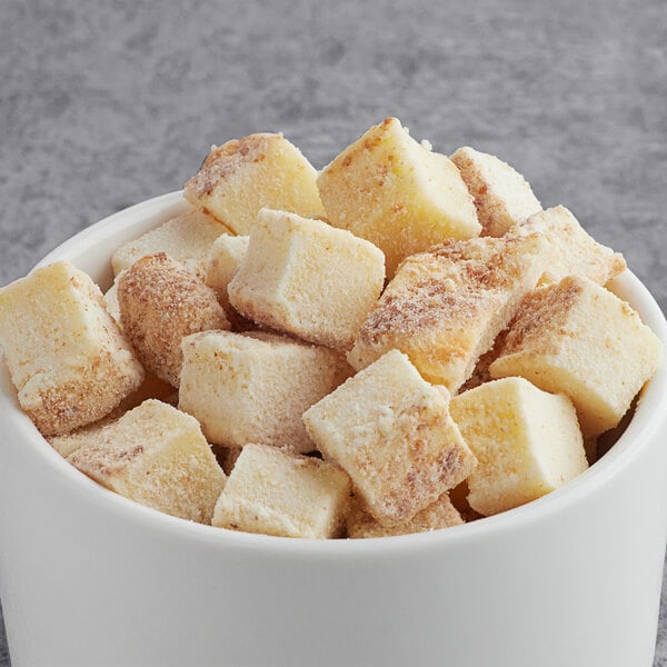 A white cup filled with brown cubes of Baked Cheesecake Pieces.