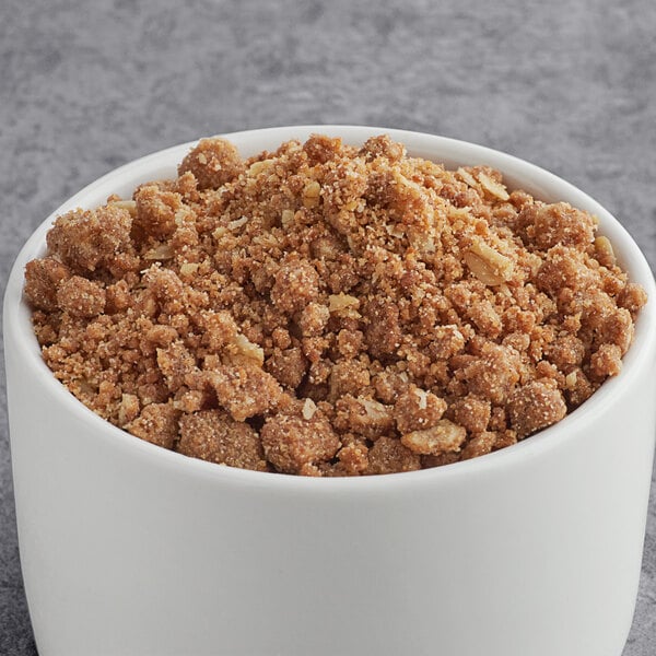 A bowl of brown granola with white cups of Cinnamon Streusel Ice Cream Topping.