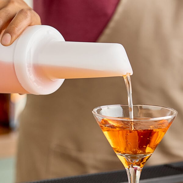 A person using a Carlisle Store N' Pour container to pour liquid into a glass.