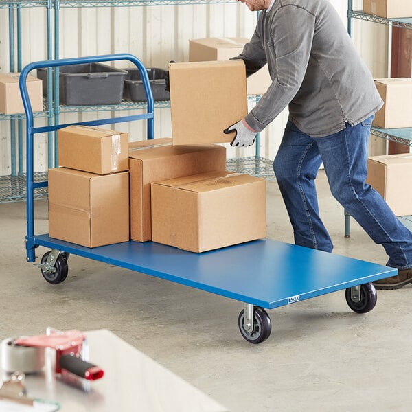 A man using a Lavex blue steel platform truck to move a grey box.