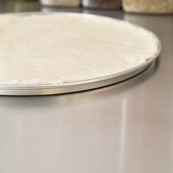 A pizza dough on an American Metalcraft aluminum pizza pan.