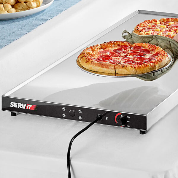 A hand placing a pizza on a ServIt heated shelf.