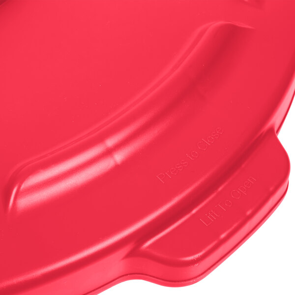 A red Rubbermaid lid for a 55 gallon trash can with a handle.