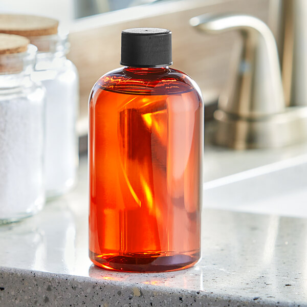 A Boston Round 8 oz. amber plastic bottle of liquid on a white counter.