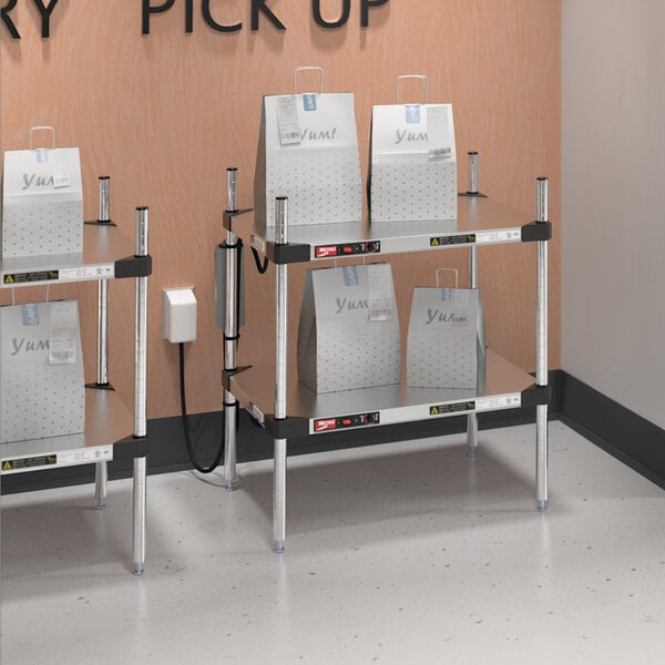 A Metro Super Erecta heated stainless steel takeout station with shelves holding bags.