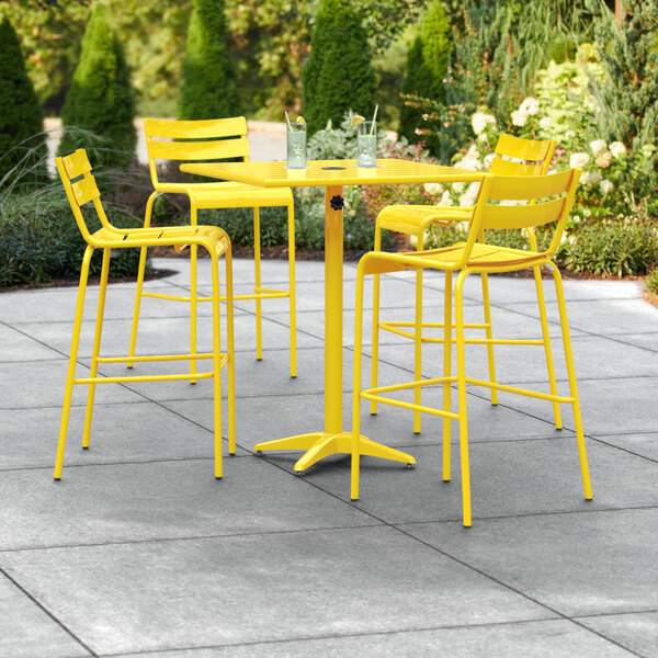 A yellow table and chairs on an outdoor patio.