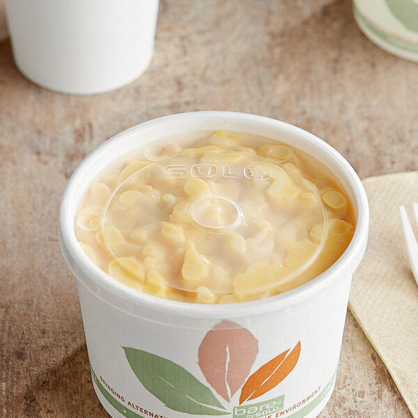 A close-up of a clear Solo vented food cup lid on a table of food.