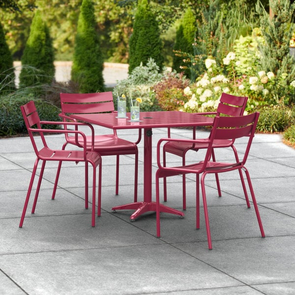 A red Lancaster Table & Seating outdoor table with chairs on a patio.