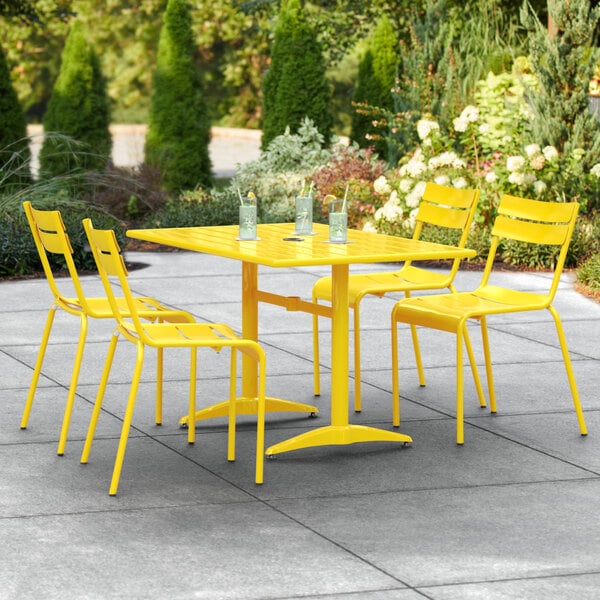 A Lancaster Table & Seating yellow table with chairs on a patio.