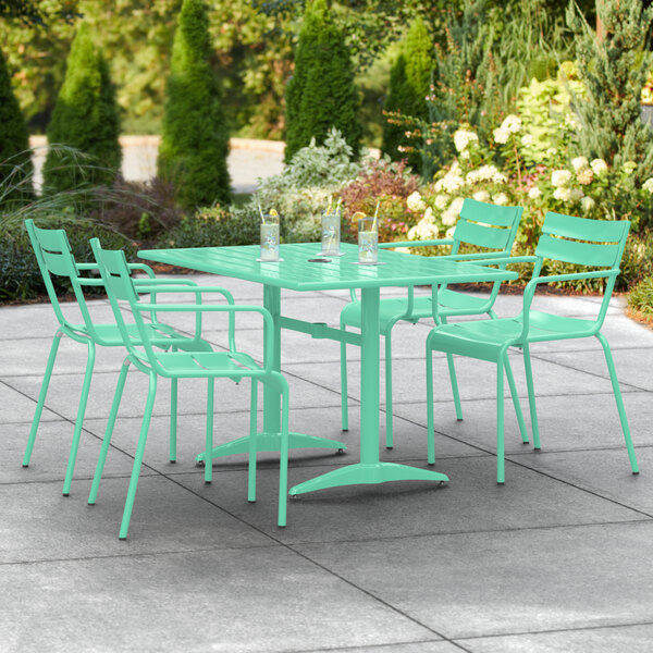 A Lancaster Table & Seating seafoam powder-coated aluminum table with 4 arm chairs on a patio.