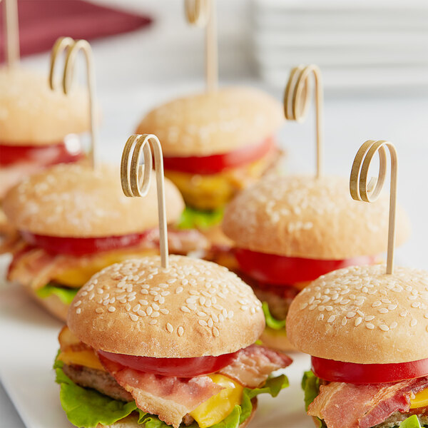 A close-up of a small hamburger with a Royal Paper bamboo pick.