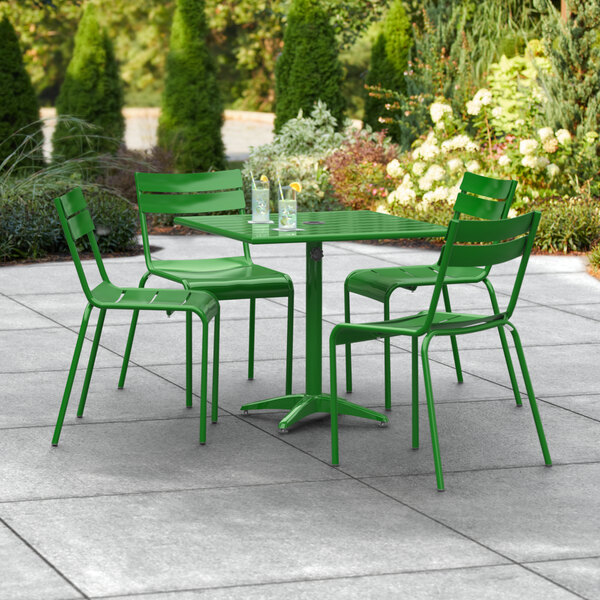 A Lancaster Table & Seating green table and chairs on a patio.