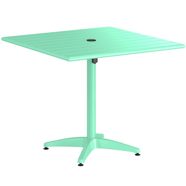 A seafoam green Lancaster Table & Seating outdoor table with a black round top.