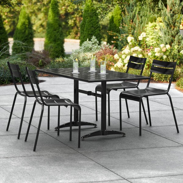 A black Lancaster Table & Seating outdoor table with chairs on a patio.