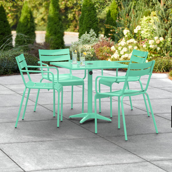 A Lancaster Table & Seating outdoor patio table in seafoam green with 4 arm chairs.