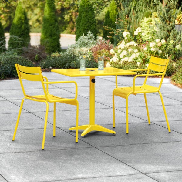 A yellow table and two chairs on an outdoor patio.