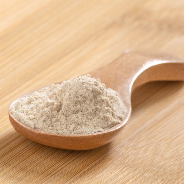 A wooden spoon holding green plantain powder.