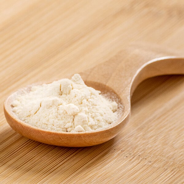 A spoonful of pineapple powder on a wooden table.