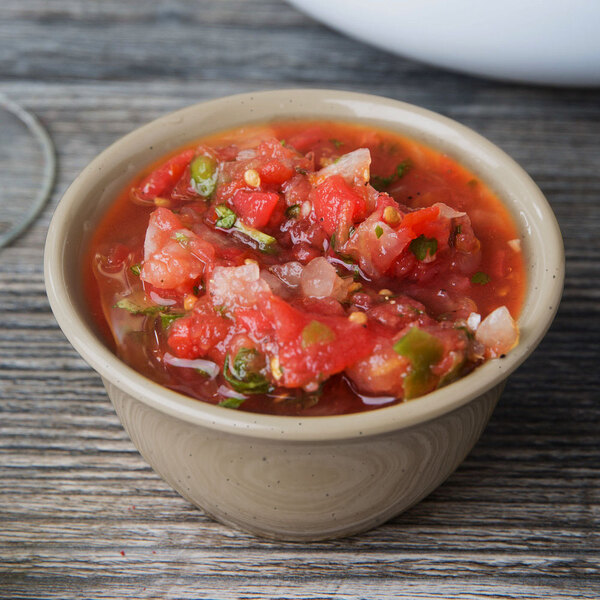 A GET Tahoe Sandstone bowl filled with salsa on a wood surface.