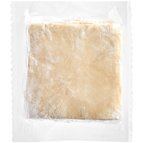 A square piece of dough in a plastic bag with a white background.