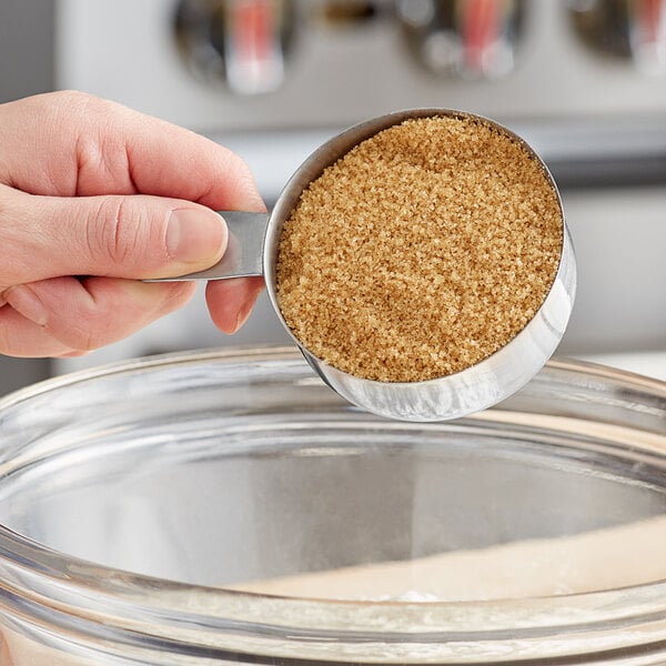 A person pouring Florida Crystals Organic Light Brown Cane Sugar into a bowl.
