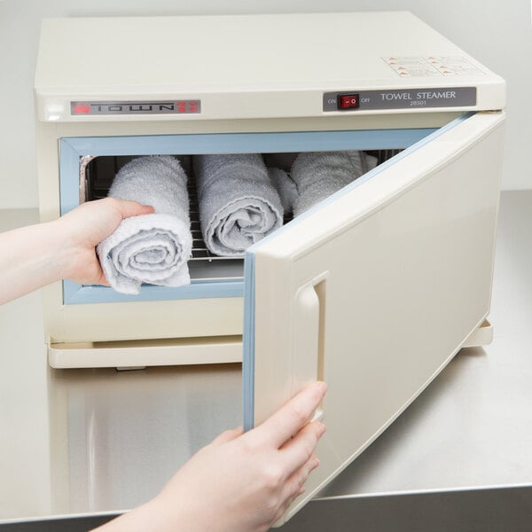 A hand holding towels in a small white oven.
