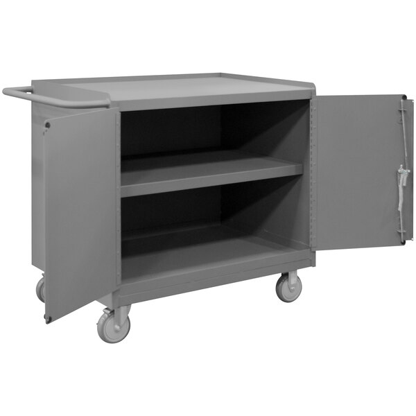 A grey metal mobile workstation with one shelf and two doors.