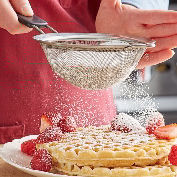 A person sifting Florida Crystals Organic 10X Powdered Raw Cane Sugar on a waffle.