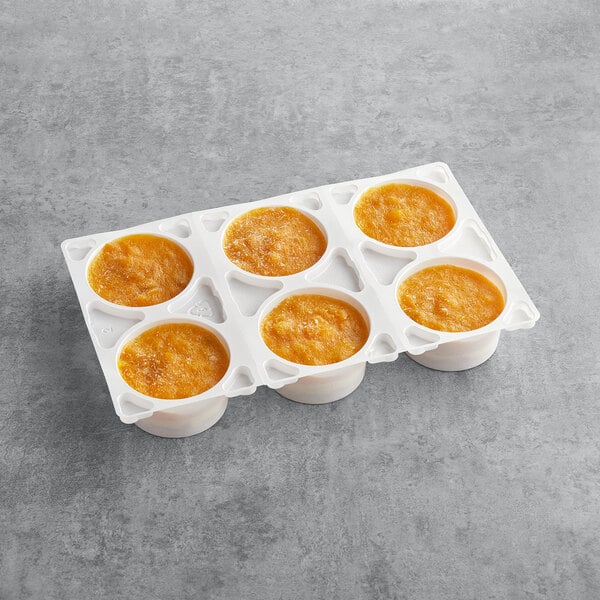 A white container with White Toque Tropical Mango Passion Cake in it with orange liquid.