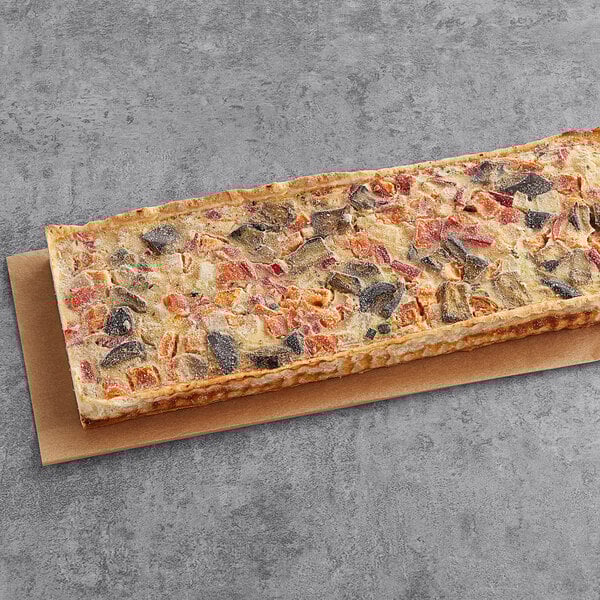 A rectangular white quiche with different toppings on a table.