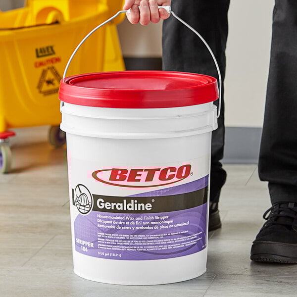 A person holding a white Betco bucket with a red lid.