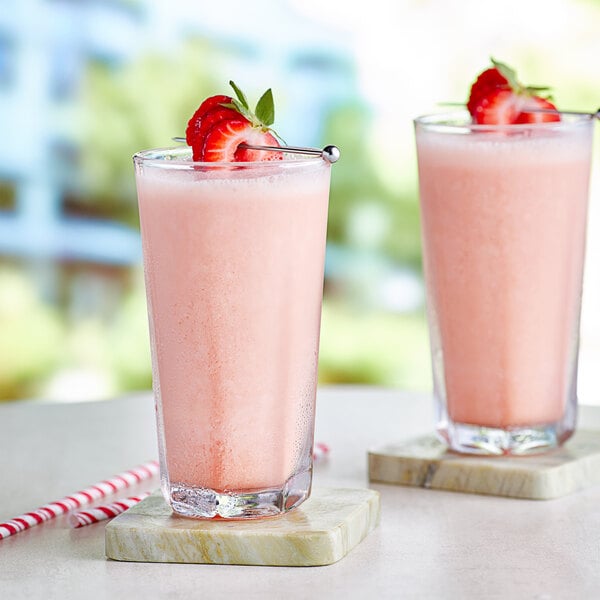 Two glasses of Capora strawberry smoothie with straws.