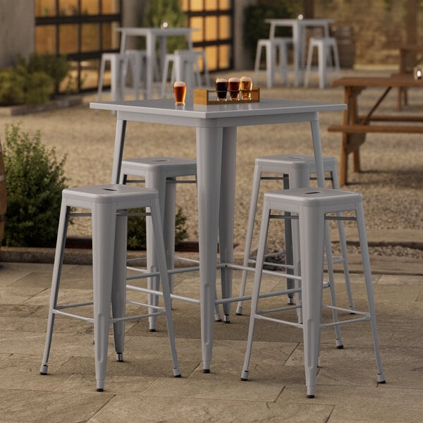 A Lancaster Table & Seating outdoor table and barstools on a patio.