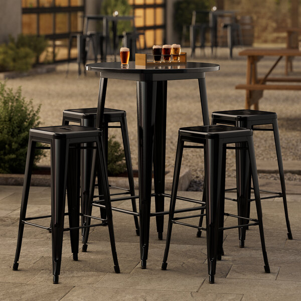 A Lancaster Table & Seating black bar table with four black barstools on an outdoor patio.