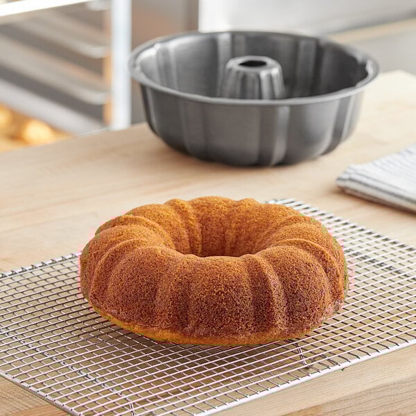 A Baker's Mark fluted bundt cake in a cake pan on a wire rack.